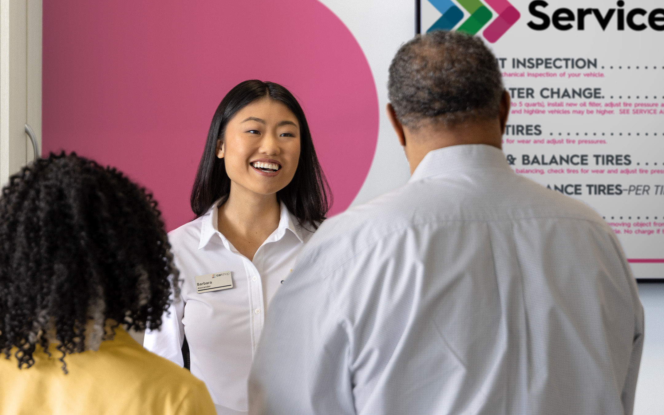 Associate smiling with clients in front of service menu