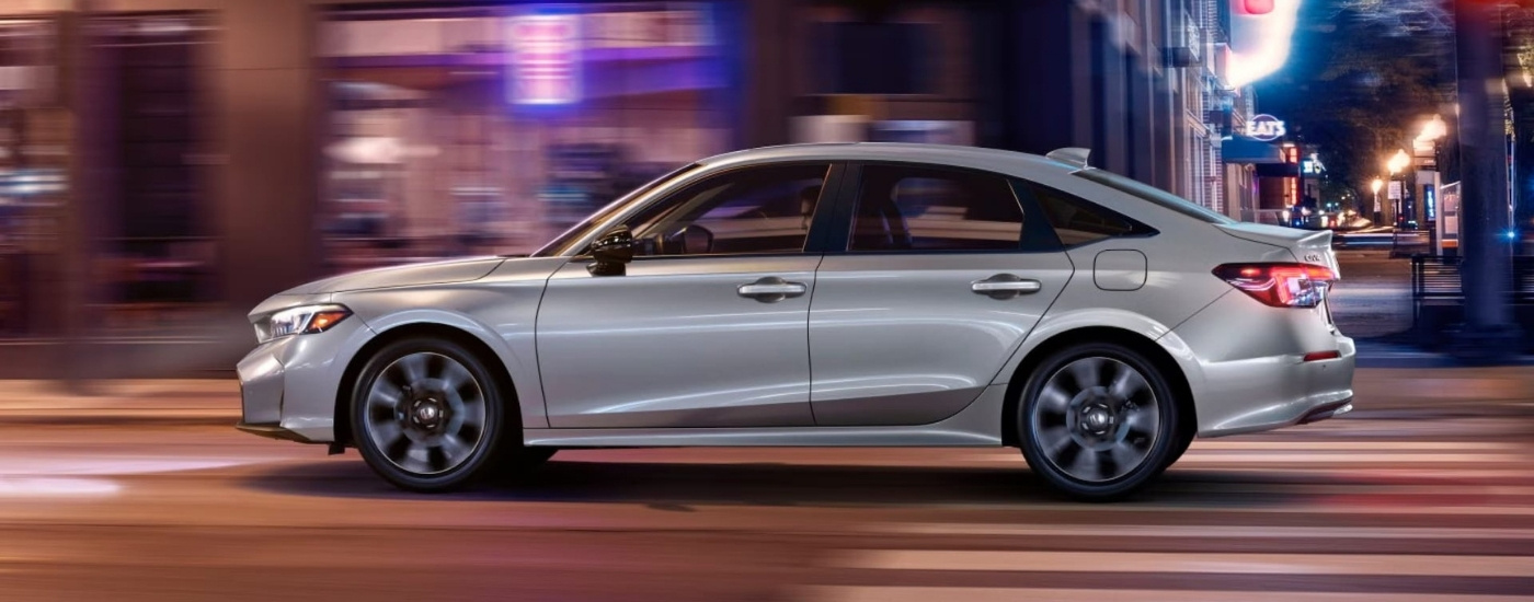 Silver 2025 Honda Civic Hybrid driving on a city street