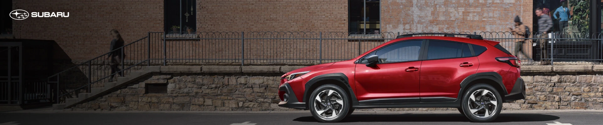 Lithium Red Pearl Subaru Crosstrek Premium parked on a street in front of a brick hardware building.