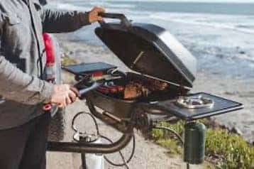 Man grilling on a portable grill by the beach