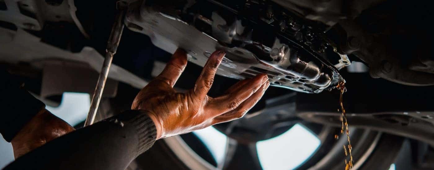 A mechanic is shown draining transmission fluid.