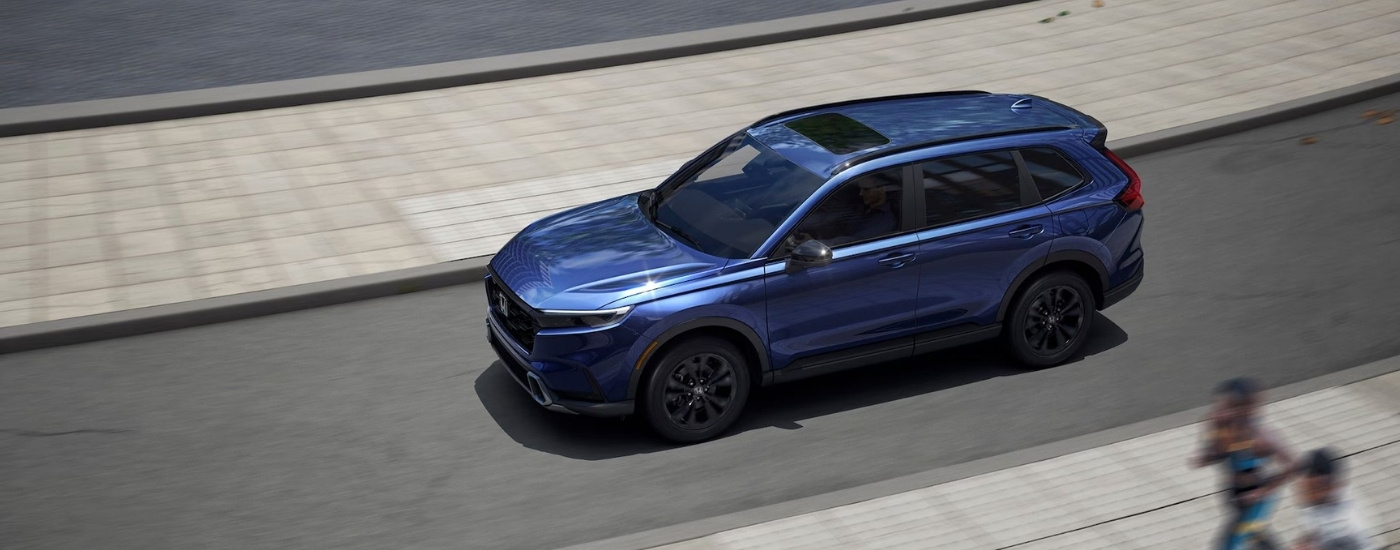 Blue 2026 Honda CR-V Hybrid Sport Touring driving on a city street