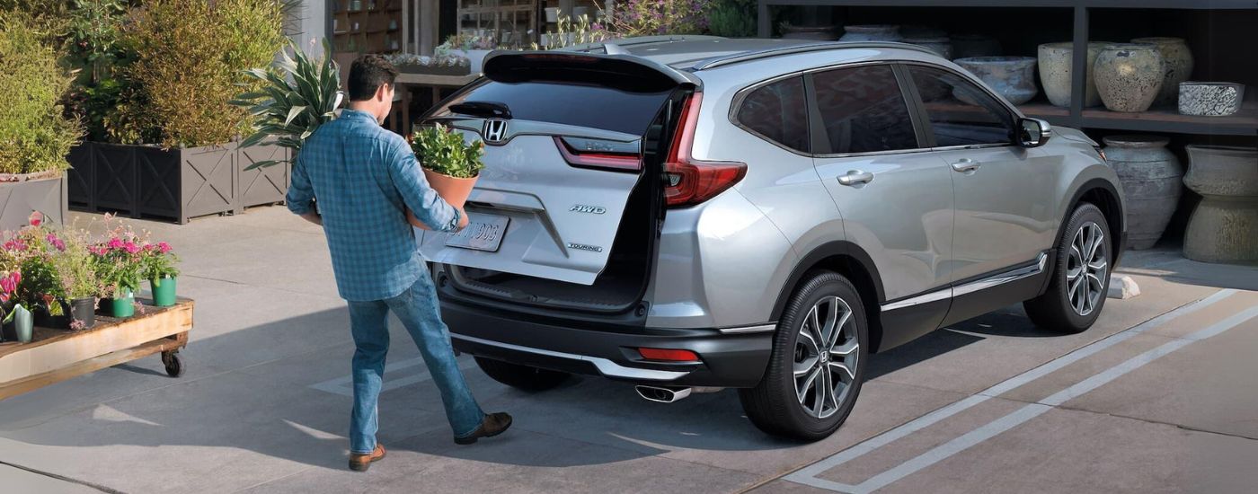 Man opening the lift-gate of a silver 2022 Honda CR-V Hybrid