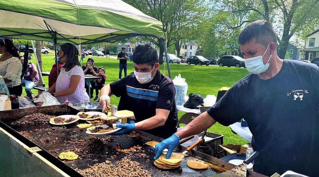 two young men cooking meat on a flat top grill for tacos at Delavan's Cinco de Mayo Festival