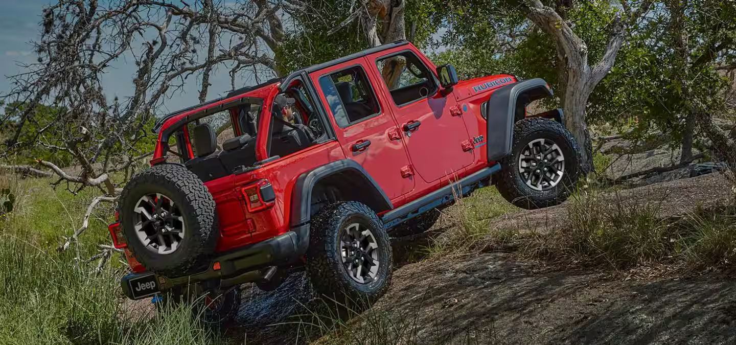 A red jeep driving up a hill.