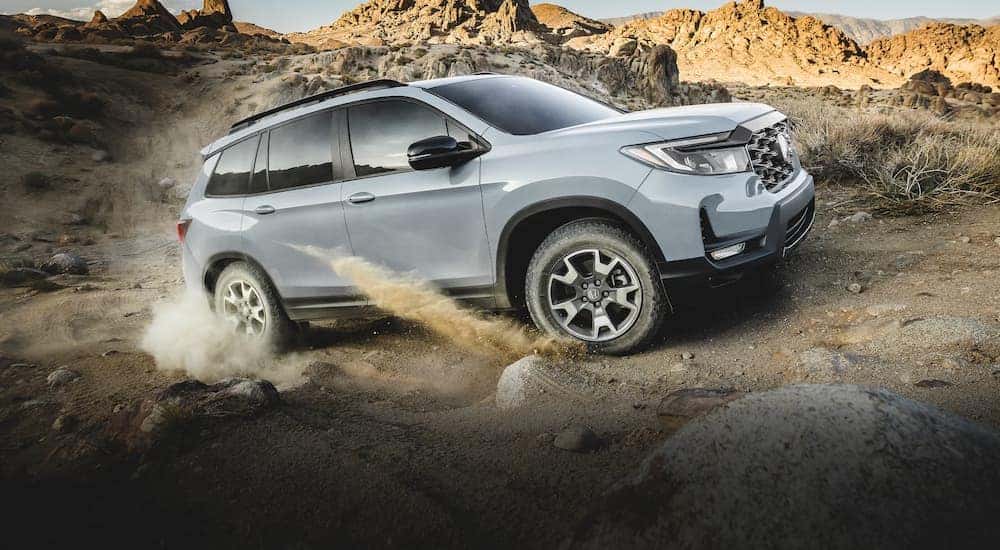 A grey 2022 Honda Passport Trailsport is shown driving on a desert trail