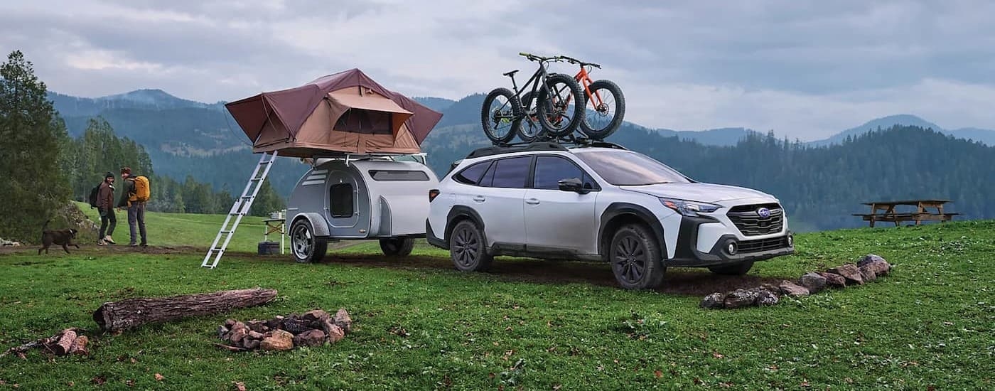 "A white 2024 Subaru Outback Onyx Edition XT is shown parked on a camp-site.