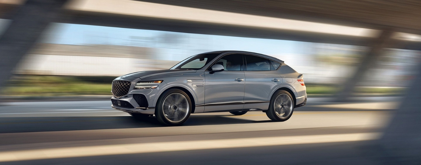 A silver 2026 Genesis GV80 Coupe driving down a highway