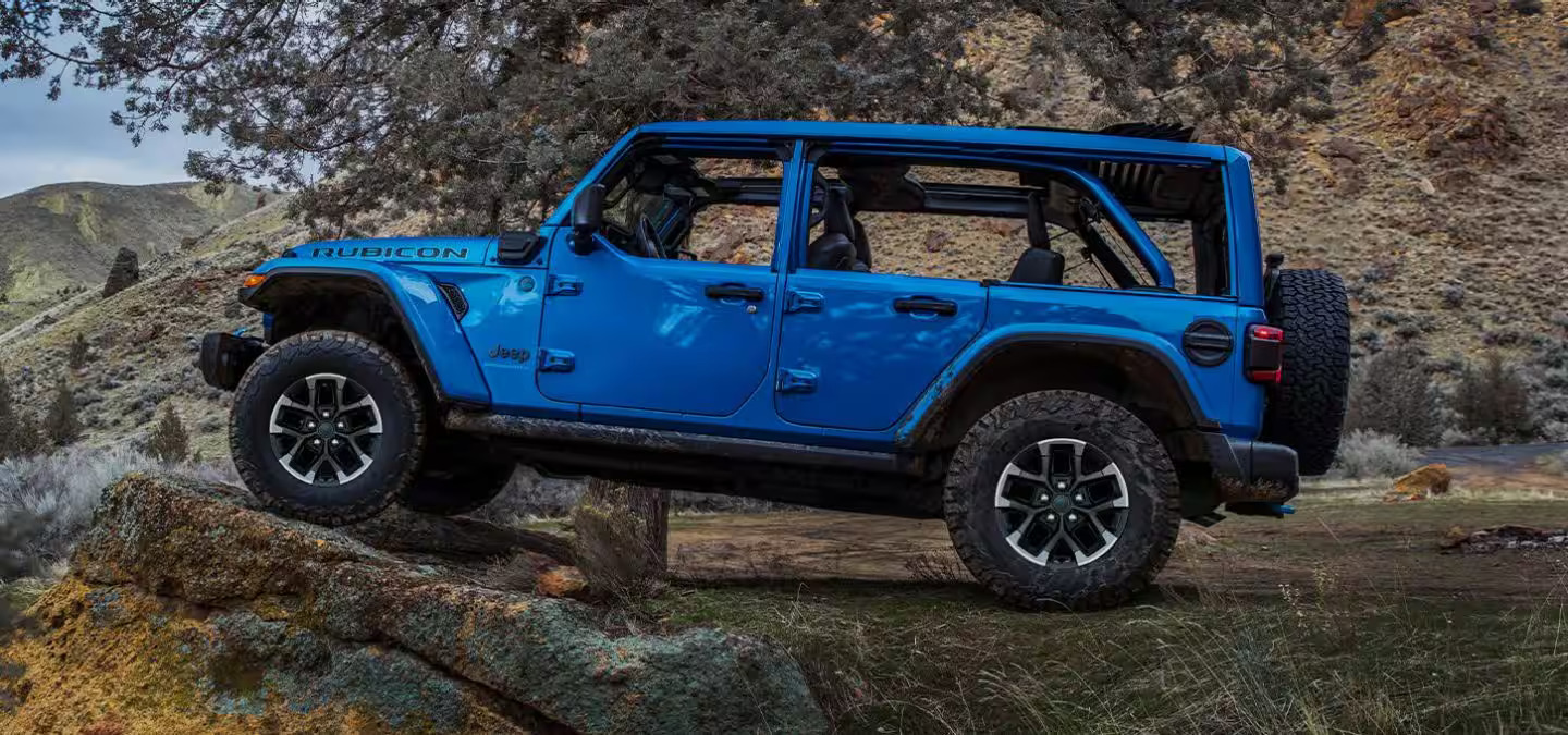 A blue jeep parked up on a rock.