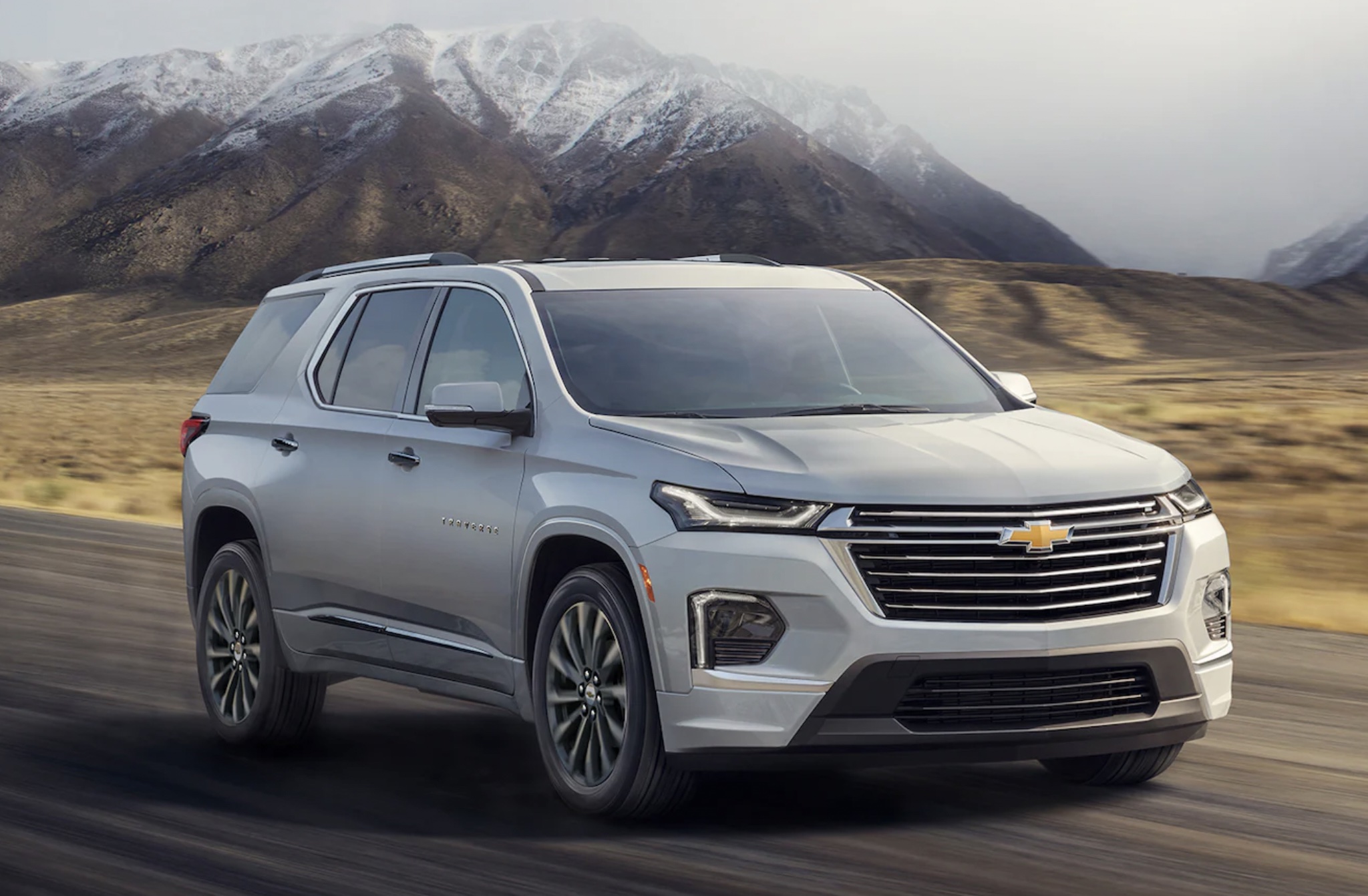 A 2022 Chevrolet Traverse midsize SUV driving on the road by mountains
