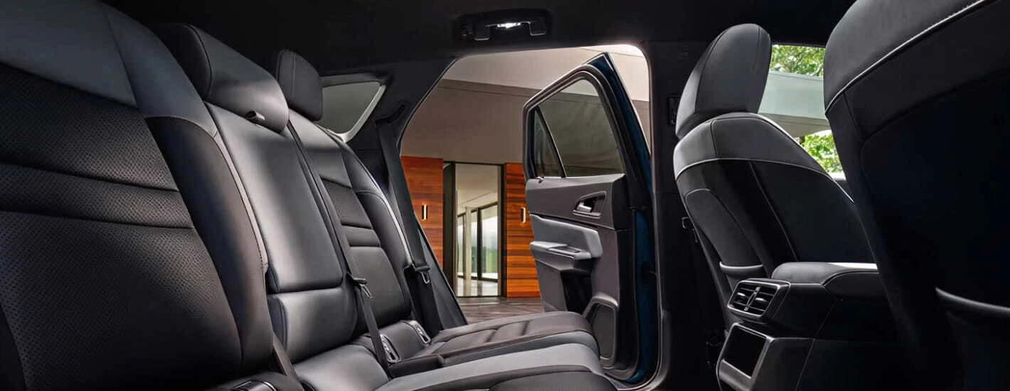 2026 Honda Prologue interior with black leather seats seen from the backseat perspective. The car door is open, revealing a modern building outside.