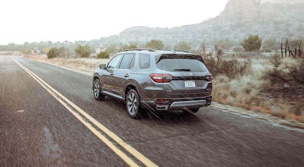 A grey 2025 Honda Pilot is shown from the rear at an angle.