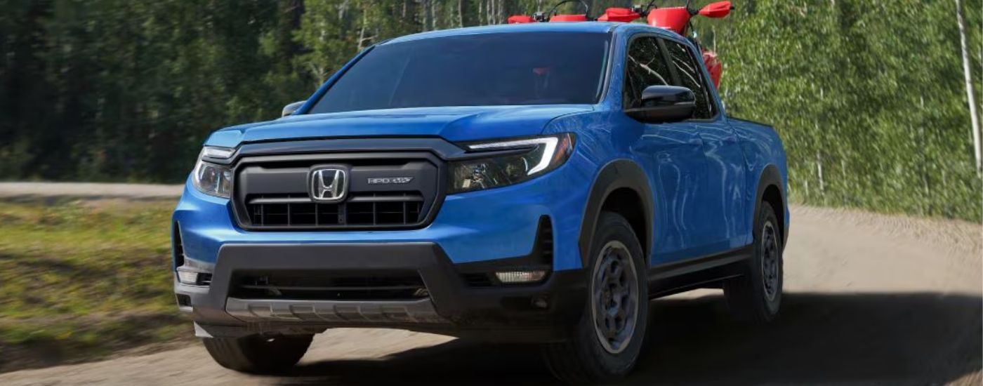 Blue 2025 Honda Ridgeline driving on a dirt road