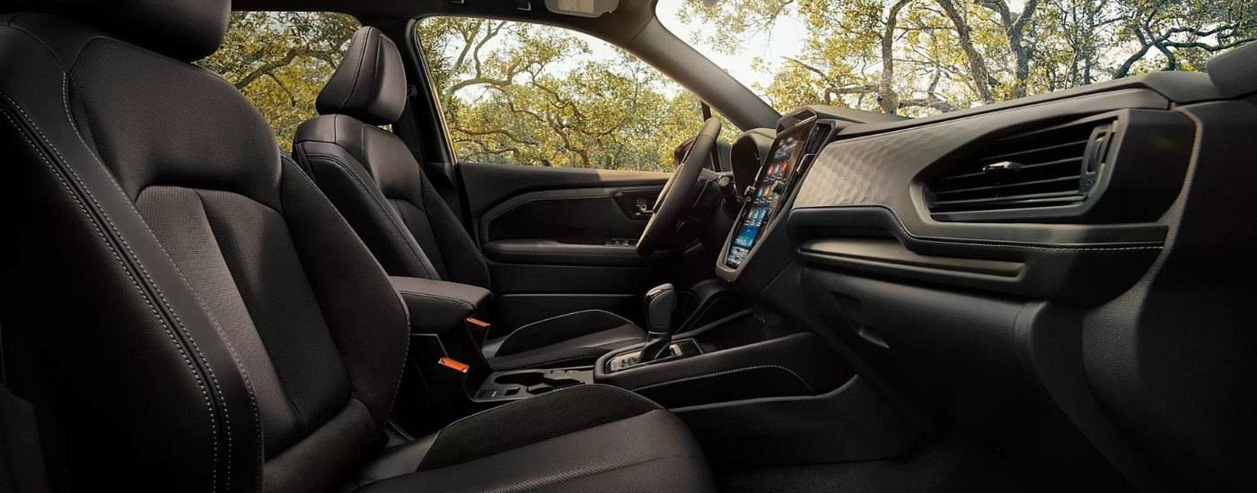 The black interior of a 2025 Subaru Forester Hybrid is shown from the passenger side.