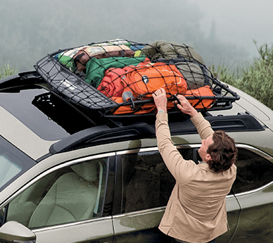 Woman securing a cargo net on a Subaru roof rack