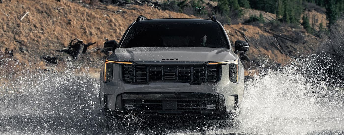 Front of a grey 2026 Kia Sorento X-Pro SX Prestige driving over a river.