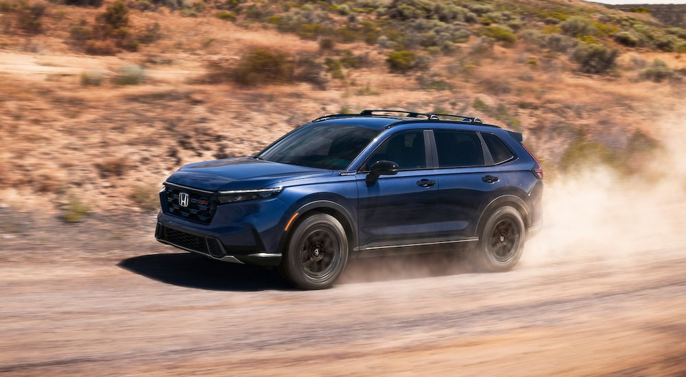 Blue 2026 Honda CR-V TrailSport Hybrid driving off-road.