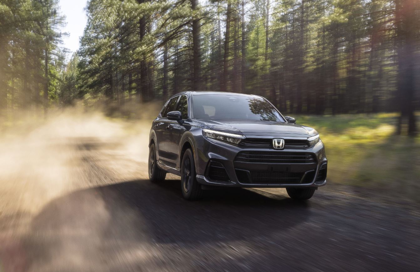 black 2025 Honda CR-V e:FCEV drives down gravel road in the middle of a forest