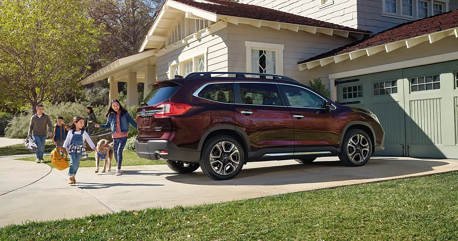 Family walking past a red Subaru Ascent in their driveway