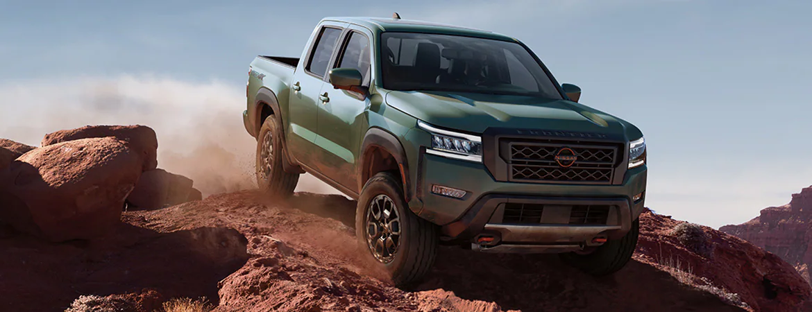 a green nissan frontier driving over a southwest canyon.