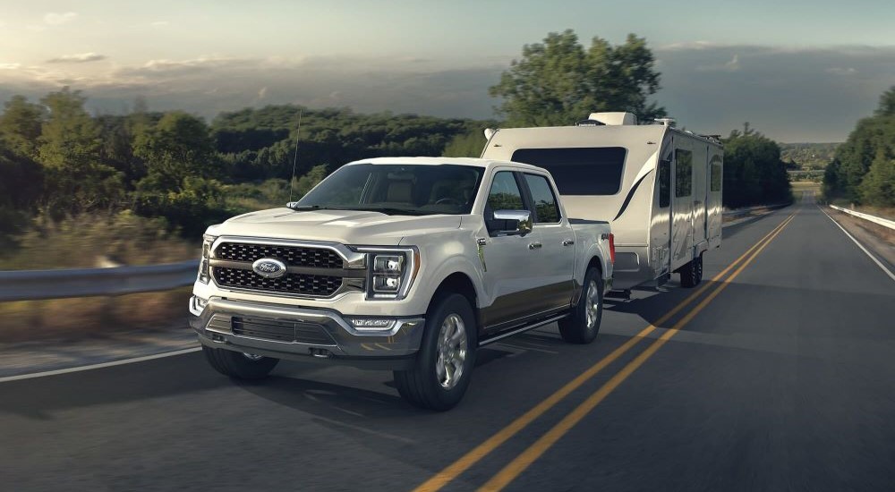 White 2022 Ford F-150 towing a camper to see used cars for sale near Crownpoint