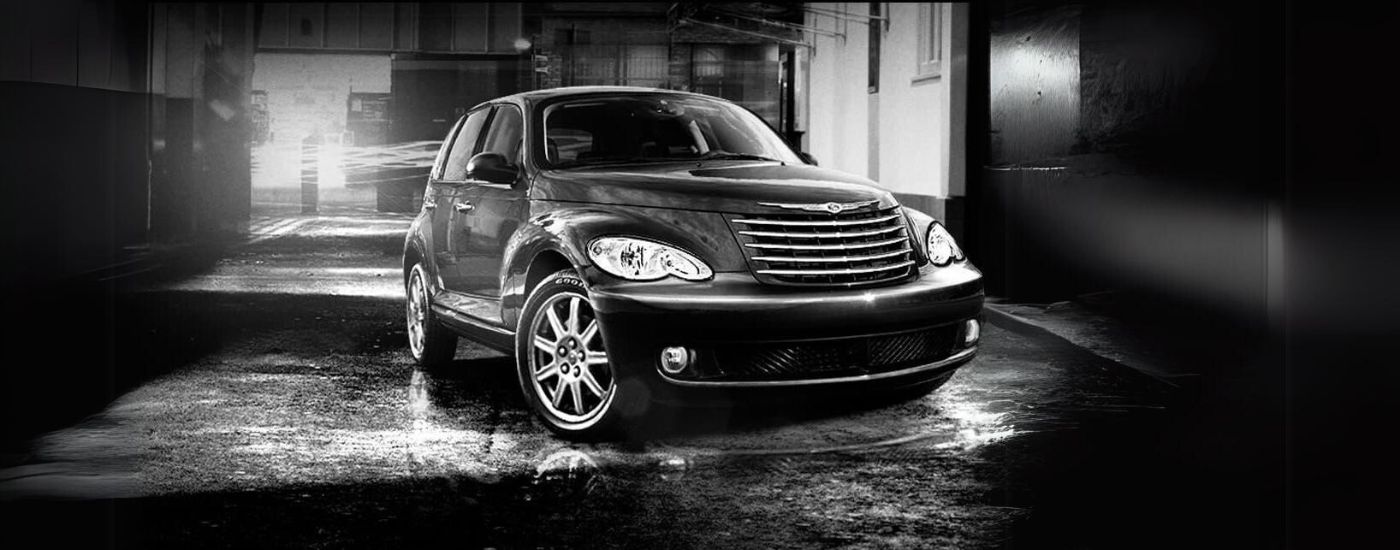 A black 2010 Chrysler PT Cruiser is shown parked in an alleyway.