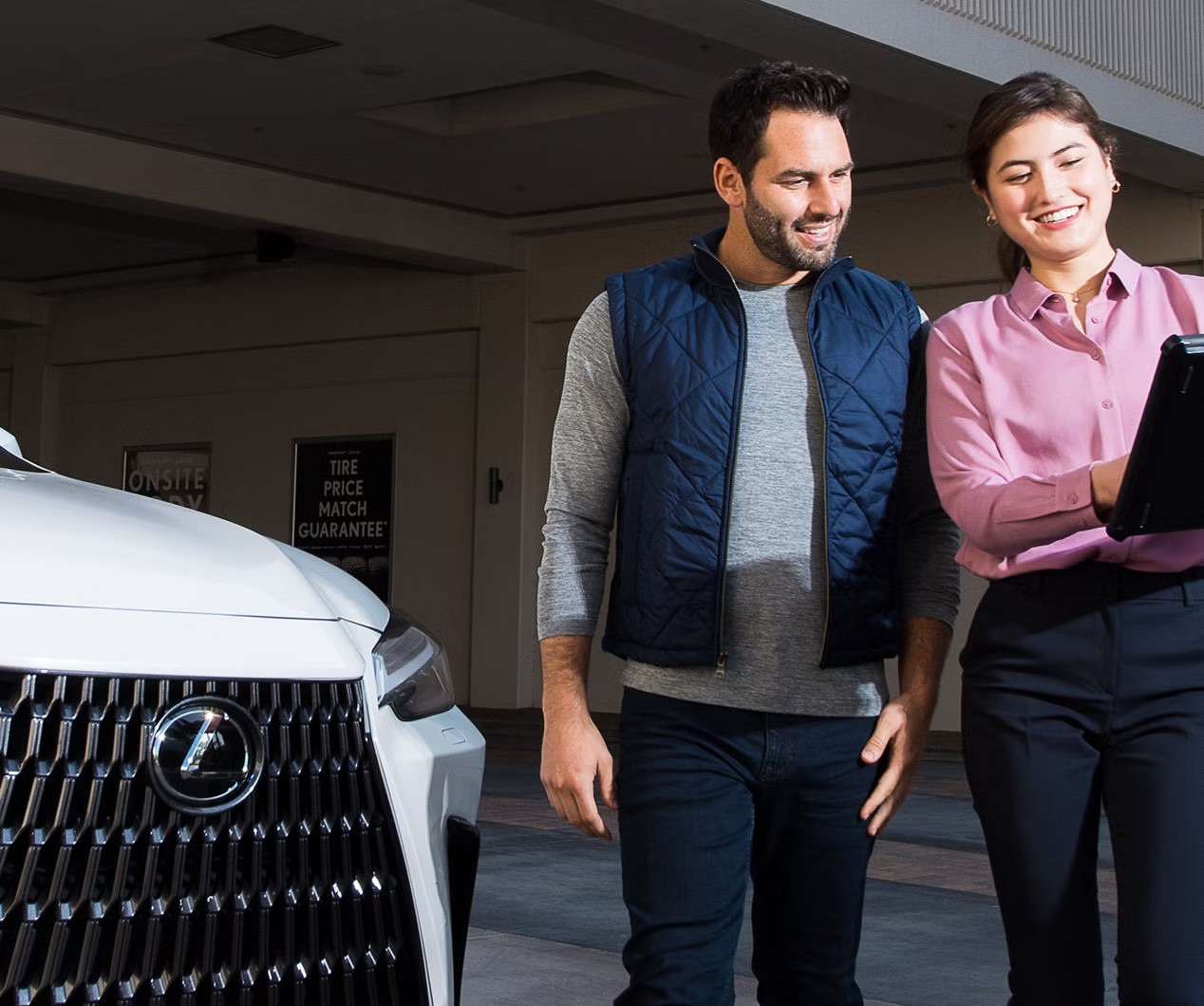Lexus vehicle specialist shown helping a guest on a tablet.