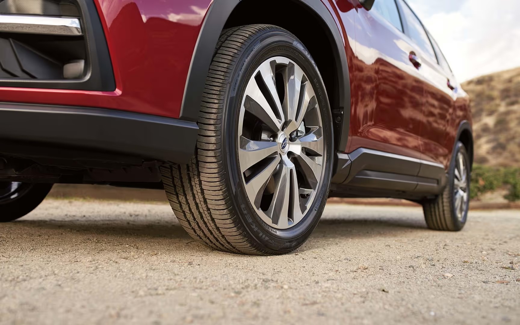 Close-up of a red Subaru SUV's wheel and tire on gravel