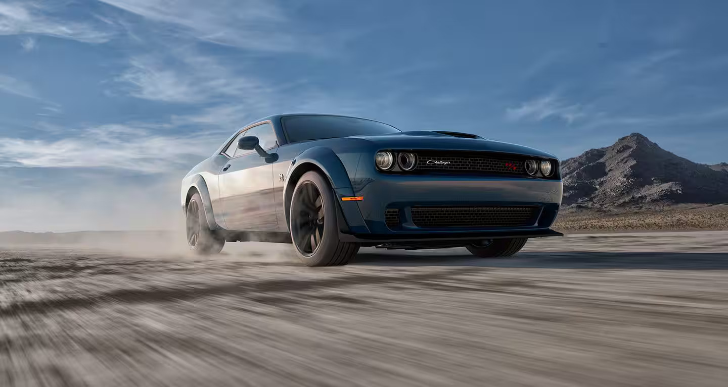 A gray dodge challenger driving on a road.