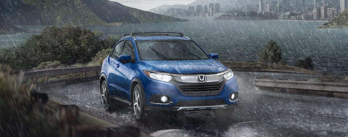 A blue 2022 Honda HR-V EX-L is shown from the front driving in the rain.