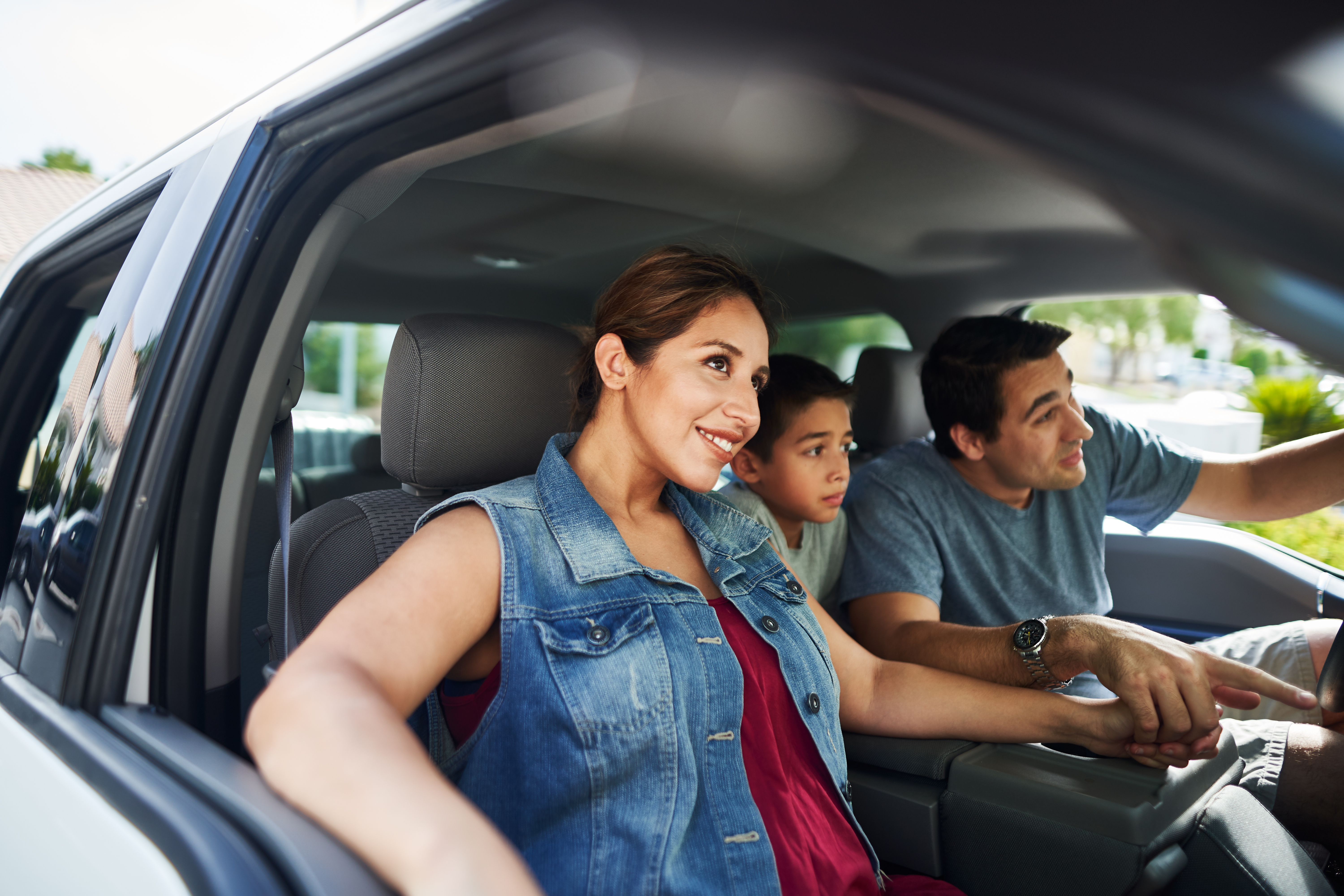 hispanic family with mother, father and son sitting in truck looking outside