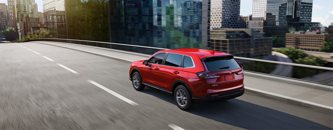 A red 2023 Honda CR-V EX is shown driving through a city.
