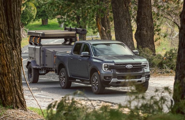 Green 2025 Ford Ranger Towing a Utility Trailer on Country Road