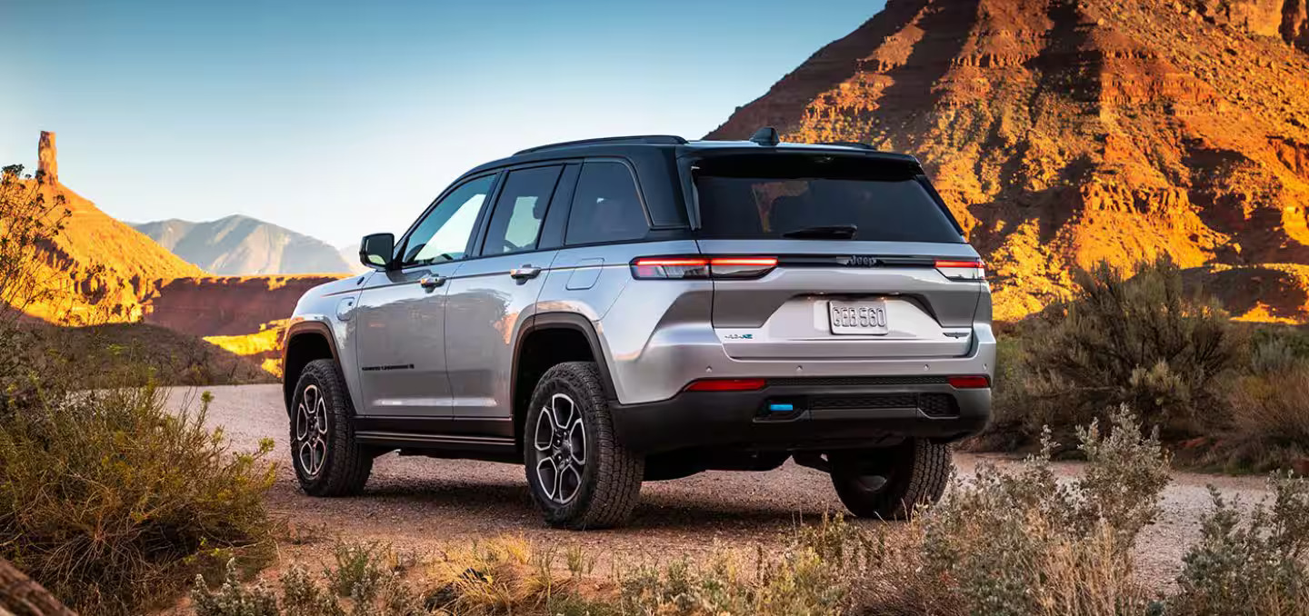 A silver jeep parked in front of a mountain.