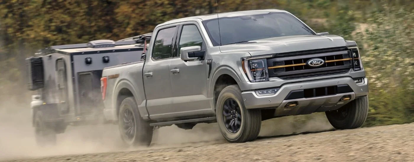 A gray 2023 Ford F-150 Tremor towing a trailer off-road.