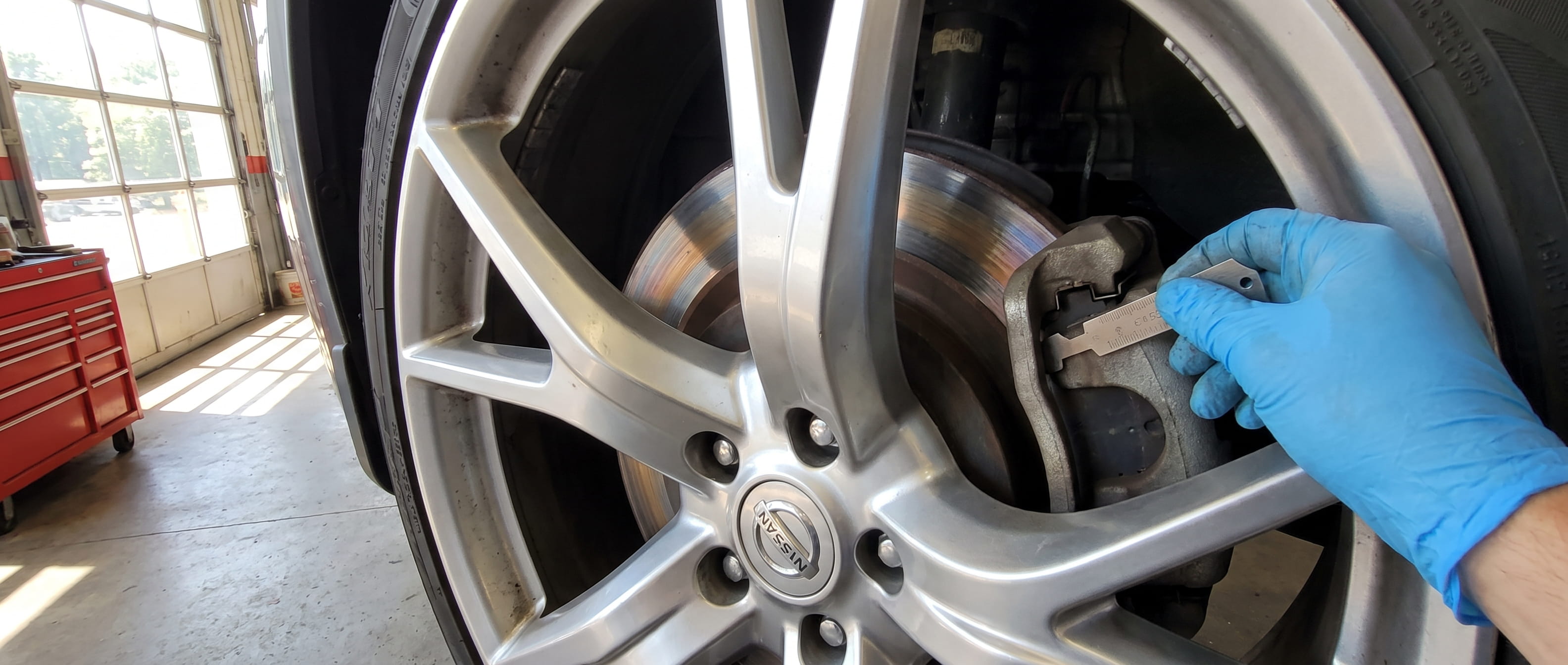 Nissan brake rotor and caliper inspection in Roswell GA service bay before long weekend road trip