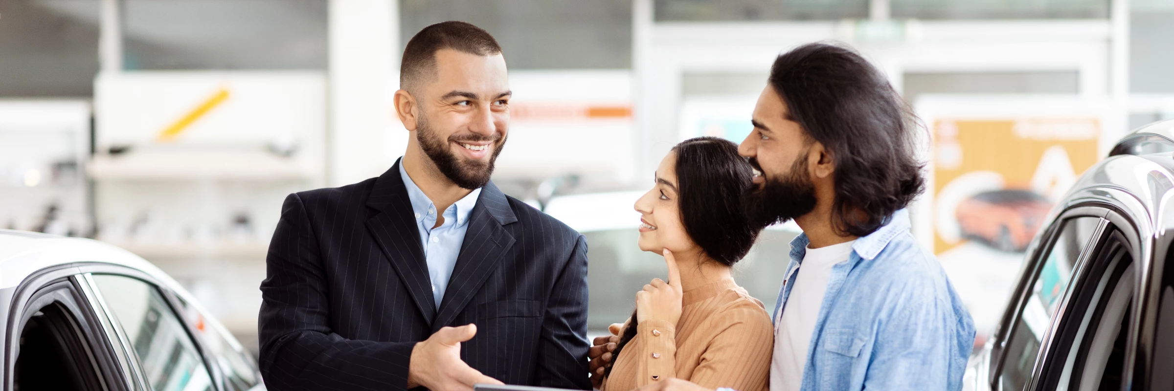 Salesperson greeting a smiling couple in a showroom
