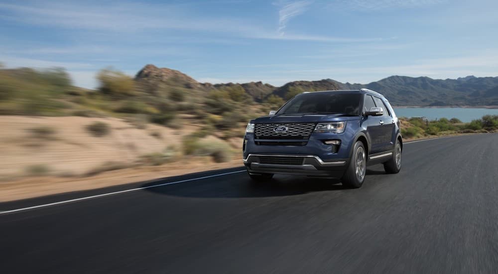 Blue 2018 Ford Explorer is shown driving past a lake after visiting a used car dealership