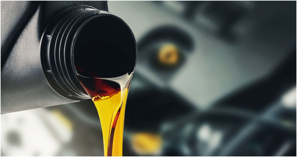 Golden motor oil pouring from a bottle into a car engine