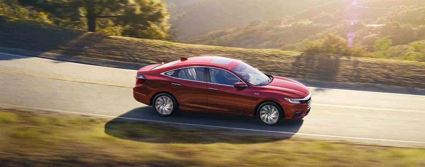 A red 2020 Honda Insight is driving on a sunny road after leaving a Honda dealer near me.