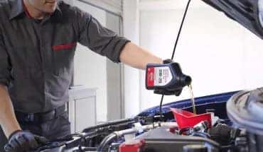 Technician pouring motor oil into a vehicle engine