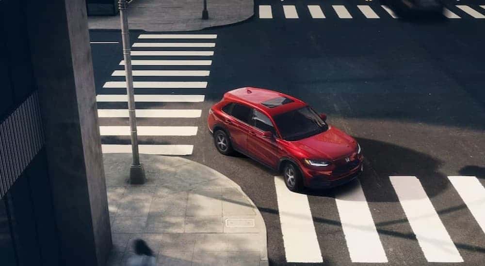 A red 2025 Honda HR-V EX-L is shown driving on a crosswalk.