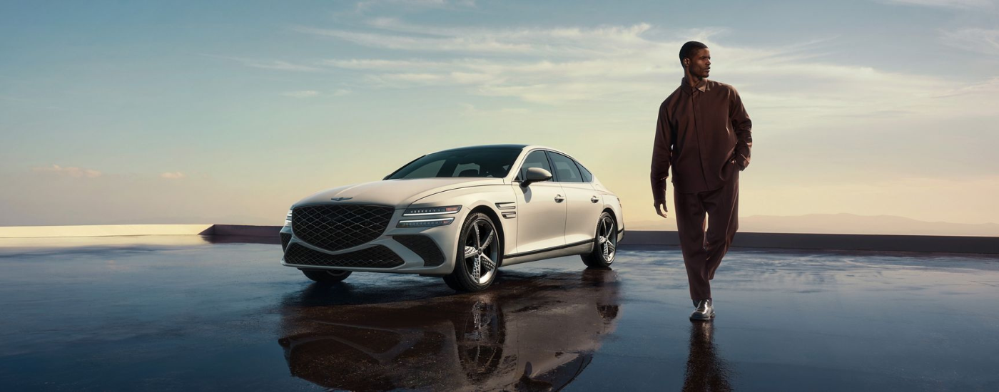 A person walking away from a white 2026 Genesis G80