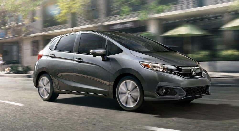 A grey 2020 Honda Fit EX-L is driving on a city street.