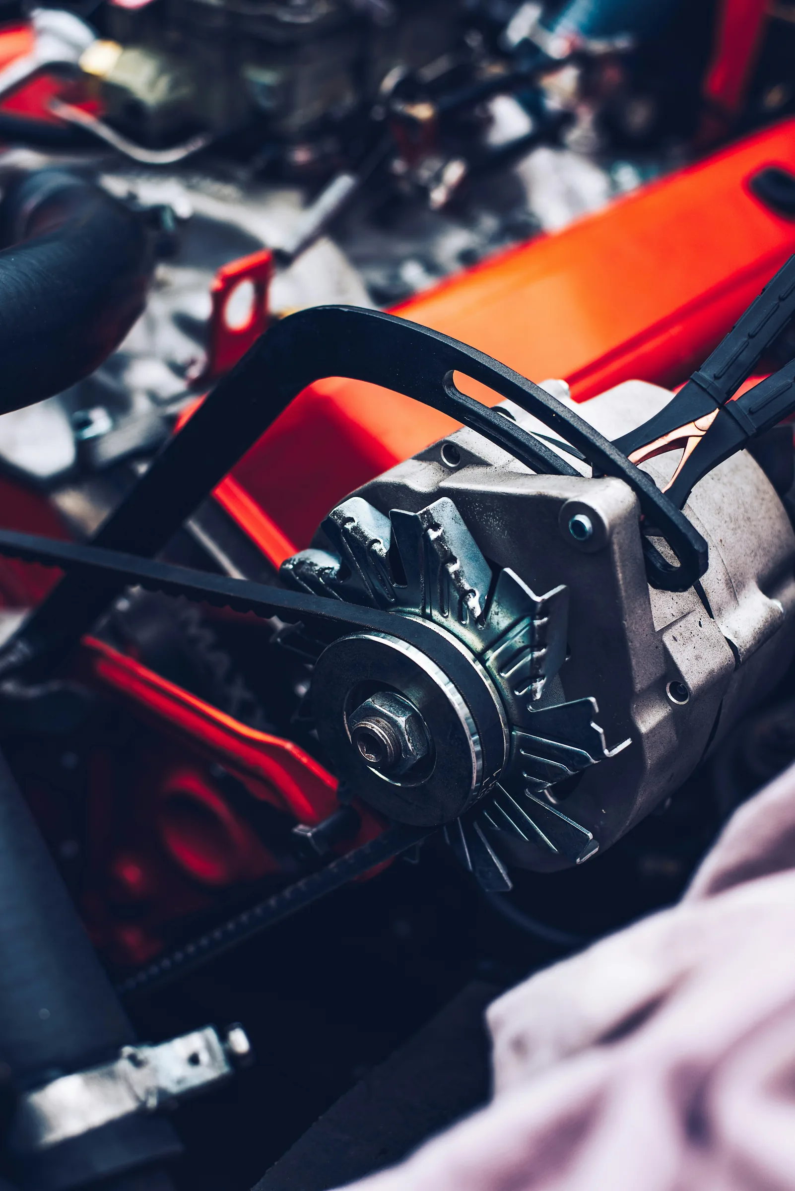 Close-up of an alternator and drive belt in a vehicle's engine bay. Alternator Service Near Olathe, KS