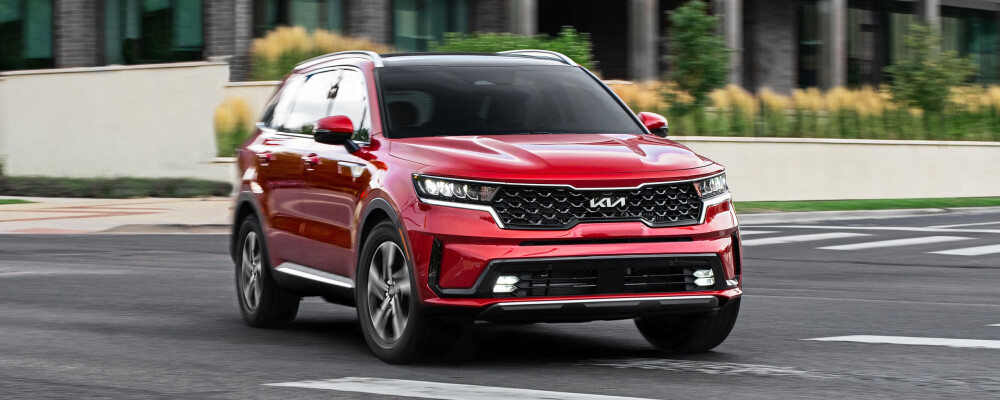 2023 Kia Sorento Hybrid in red, showcasing sleek exterior design and hybrid efficiency on urban road.