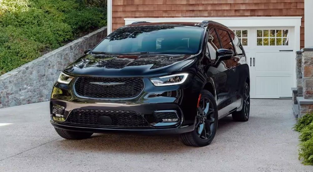 A black 2023 Chrysler Pacifica is shown parked in front of a garage after leaving a Chrysler dealer.