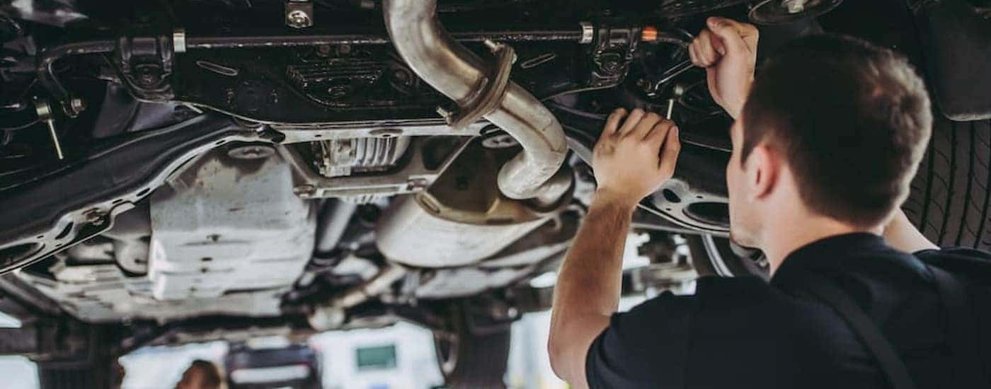 A mechanic is shown inspecting a vehicle at a Rochester certified pre-owned Honda dealer.