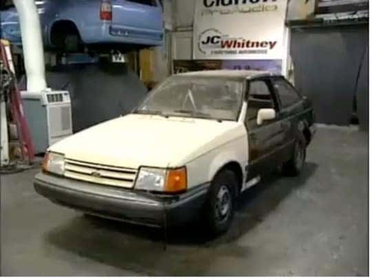 Worn white Ford Escort in a repair shop