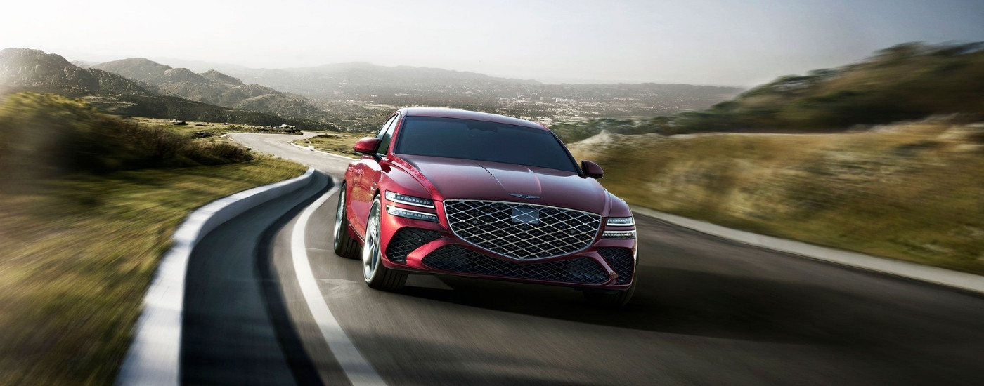 Red 2025 Genesis G80 for sale driving on a winding road